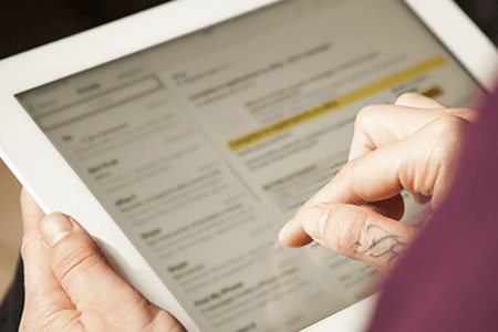 Person schaut sich E-Mail-Betreffzeilen auf Tablet an