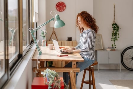 Frau schreibt eine E-Mail am Laptop und entscheidet zwischen Cc und Bcc