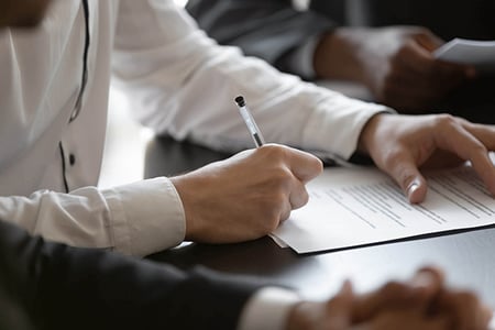 Frau unterschreibt Formular zur Markenanmeldung mit Kugelschreiber
