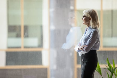 Frau steht vor Fenster und schaut hinaus