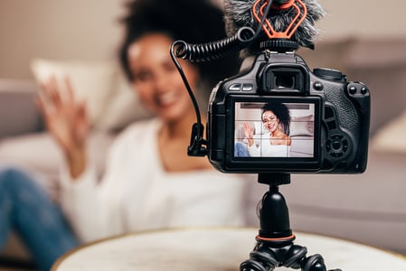 Kamera im Vordergrund steht vor Influencerin