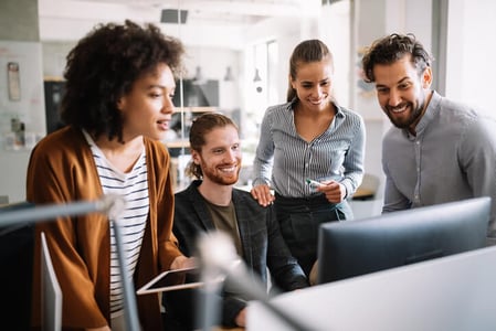 Team steht vor Computer und sucht nach passender Unternehmenssoftware