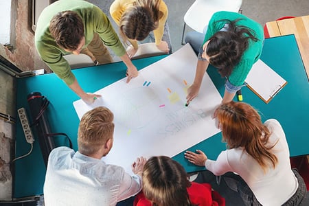 Personen arbeiten Plan für Agiles Marketing auf Papier aus