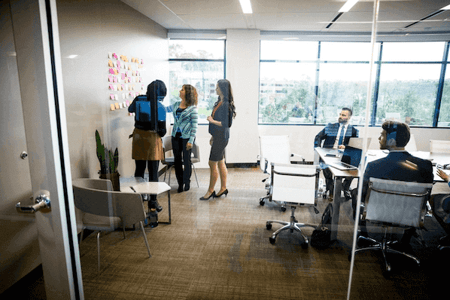 Kolleginnen und Kollegen besprechen agiles Projektmanagement in Meetingraum