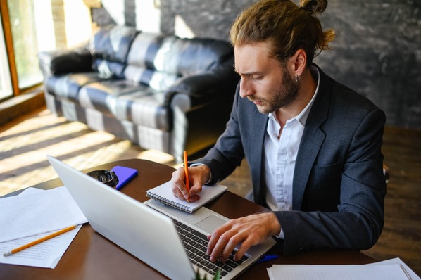 Ein Mann sitzt am Laptop und erstellt einen Arbeitsplan nach der ALPEN-Methode