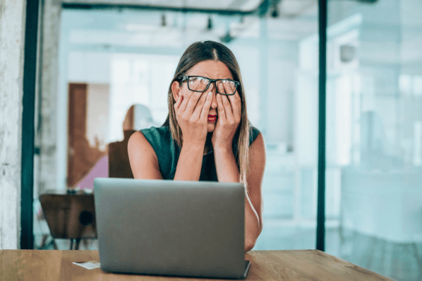 Frau vor Laptop reibt sich Augen aufgrund von Antriebslosigkeit