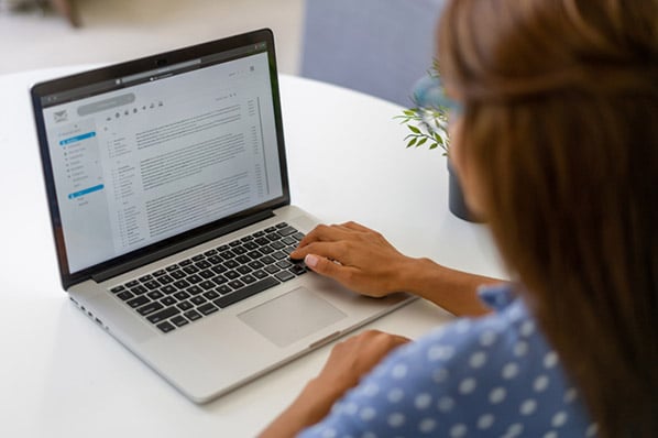 Frau am Laptop schaut durch E-Mails als Beispiel für asynchrone Kommunikation