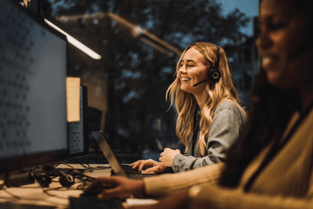 Call Center Agent mit Headset sitzt vor Computer im Büro