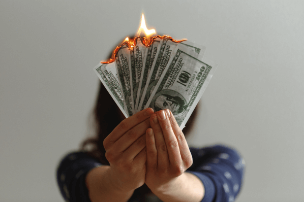 Frau hält brennendes Geld in der Hand symbolisierend für Cash Burn Rate