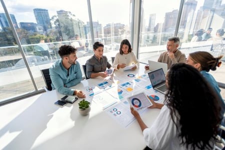 Gruppe von Menschen sitzt am Tisch und beschäftigt sich mit Competitive Intelligence