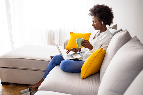 Frau auf Sofa mit Tasse in der Hand erstellt CSS-Border für Website am Laptop