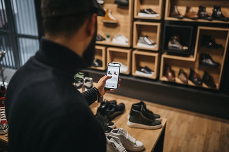 Mann in Geschäft überprüft Preise am Handy symbolisierend für Customer Journey
