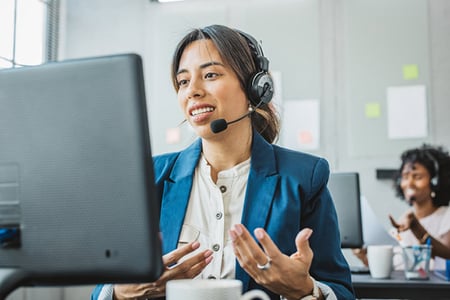 Frau mit Headset benutzt Down-Selling als Vertriebsstrategie