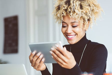 Lächelnde Frau zuhause am Tablet arbeitet mit Facebook-Algorithmus