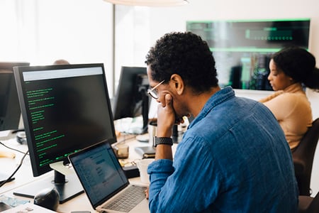 Mann vor Laptop und Tablet arbeitet an Google-Algorithmus