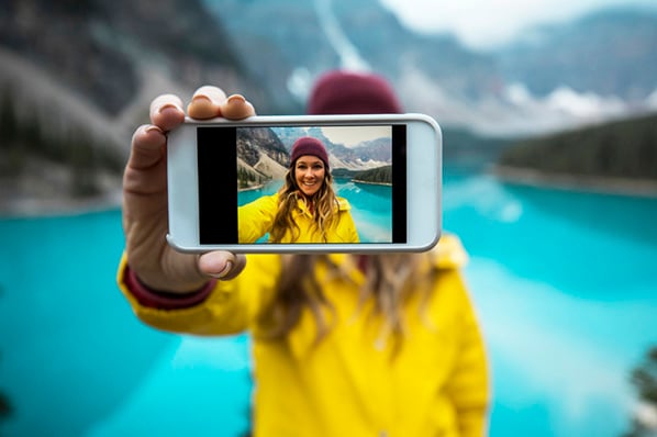 Frau vor See macht mit IPhone Selfie im HEIC-Format