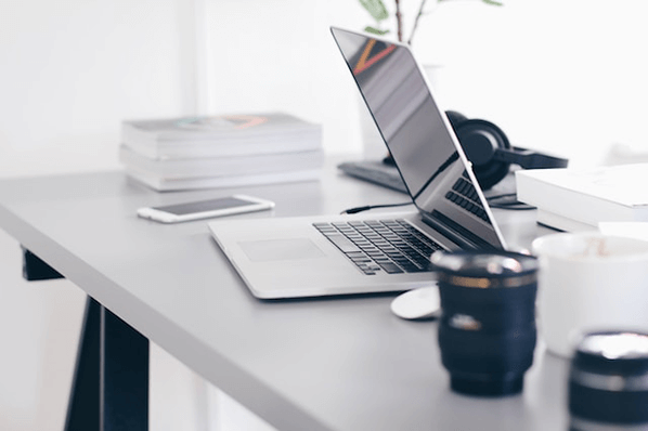 Laptop und Kaffeebecher am Schreibtisch