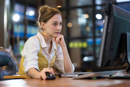 Frau in Office am Monitor mit Maus nutzt Hybrid Cloud bei der Arbeit