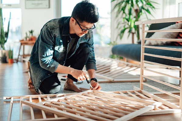 Mann zuhause baut selbst Bett auf und demonstriert IKEA-Effekt