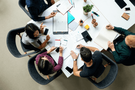 Team sitzt am Tisch und beschäftigt sich mit Informationsmanagement