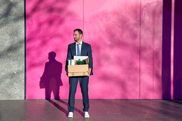 Mann in Business Anzug mit Box in der Hand freut sich über interne Bewerbung