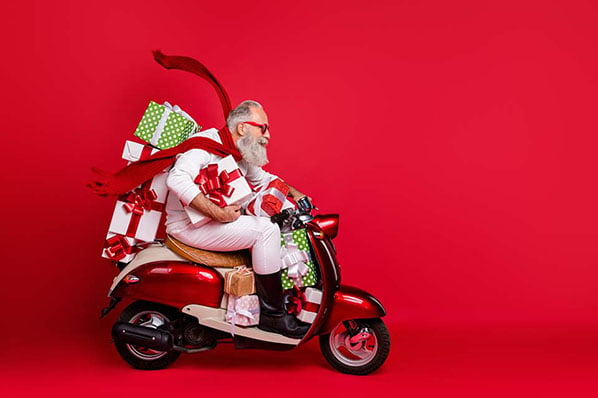 Ein Mann der Geschenke auf einem Roller verteilt als Symbol fuer Kundenbindung an Weihnachten