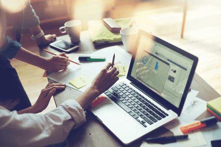 Personen vor Laptop entwickeln B2B-Online-Marketing-Strategie