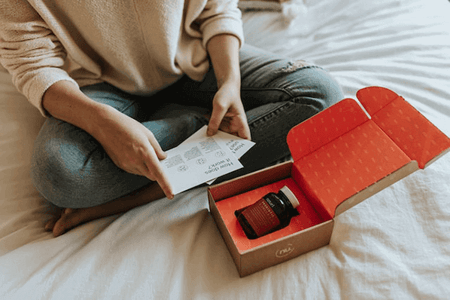 Frau öffnet Paket und betrachtet die Paketbeilagen