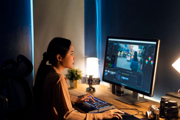 Frau nachts zuhause arbeitet mit Photoshop-Plugins am Monitor