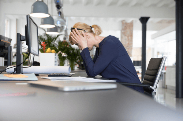 Frau sitzt krank am Arbeitsplatz aufgrund von Präsentismus