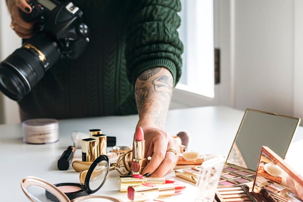 Frau bereitet Produktfotografie mit Lippenstift auf Tisch vor