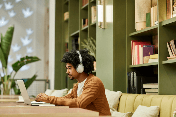 Person sitzt im Cafe und hört Musik bei der Arbeit, um die Produktivität zu steigern