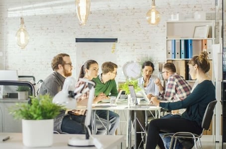 Marketing und Vertriebsteam sitzen am Tisch und üben sich in Zusammenarbeit