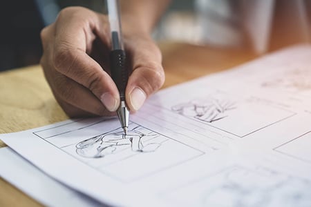 Person zeichnet Storyboard auf Papier