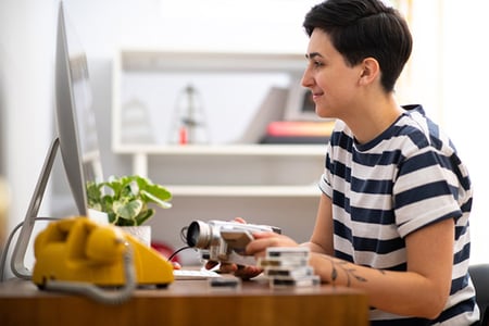 Frau am Monitor mit Kamera in Hand arbeitet mit WebM