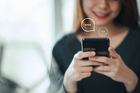 Frau erstellt eine WhatsApp Broadcast Liste am Smartphone
