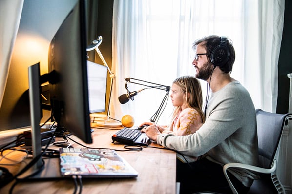 Dank Work-Life-Integration sitzt Mann vor Computer mit Kind auf Schoß