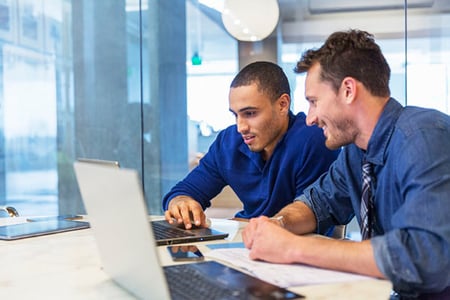 Zwei Männer in blau am Laptop schauen sich beste Zendesk-Alternativen an