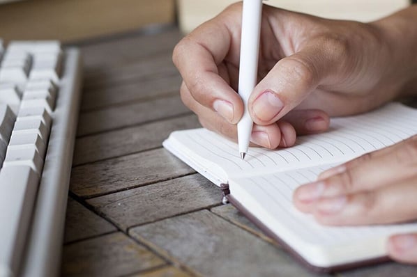Person schreibt mit Stift in Notebook