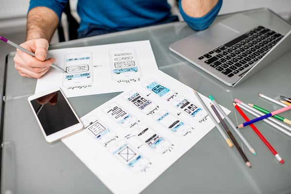 Mann zeichnet Konzept für Mobile-First-Website als Mockup auf Papier