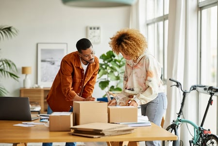 Mitarbeitende kleinen Unternehmens packen Produkte fuer Zielgruppe