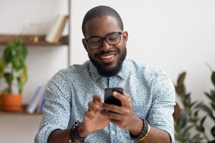 Mann hält Smartphone in beiden Händen und lächelt