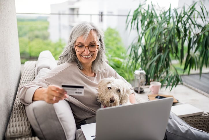 Frau-sitzt-mit-Hund-auf-dem-Sofa-und-betreibt-Online-Shopping