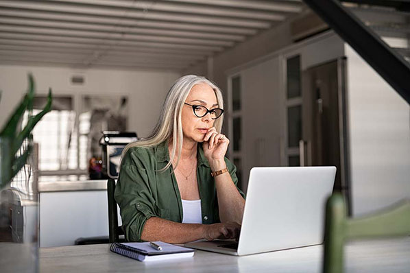 Frau mit Brille arbeitet mit Laptop an Webanalyse