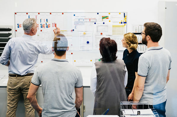 Team berechnet Beschäftigungsgrad ihres Unternehmens an Whiteboard