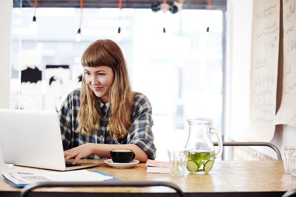 Frau arbeitet in Cafe am Laptop an Blog-Design