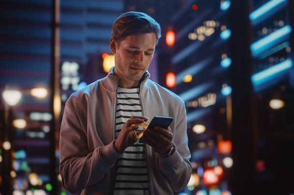 Mann auf dunkler Straße informiert sich über DeFi auf Smartphone