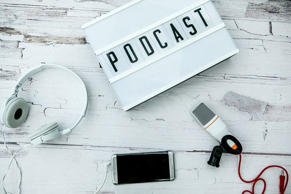 Mikrophon, Smartphone, Kopfhörer, Schriftzug symbolisieren digitales Infoprodukt Podcast 