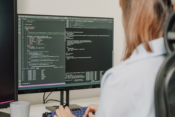 Frau am Monitor arbeitet mit HTML-Grundgerüst im Code