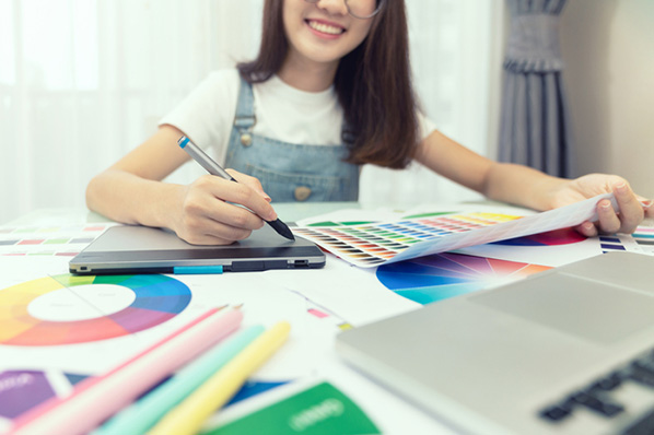 Frau am Tisch mit Laptop und Tablet sucht HTML-Hintergrundfarbe mit Farbtabellen aus